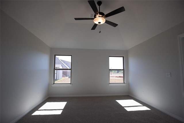 empty room with dark colored carpet, plenty of natural light, lofted ceiling, and ceiling fan