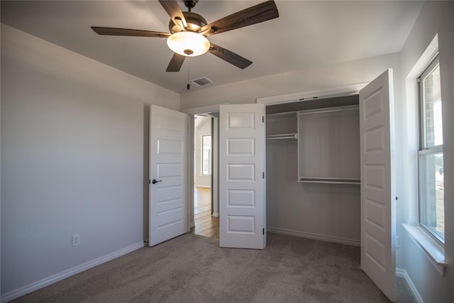 unfurnished bedroom featuring carpet floors, a closet, multiple windows, and ceiling fan