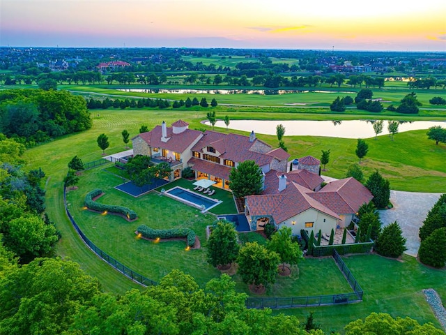 aerial view at dusk featuring a water view