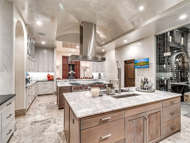 kitchen with light stone countertops, a large island with sink, lofted ceiling, island range hood, and high end stainless steel range