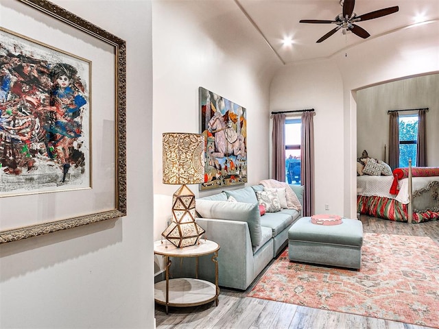 living room with ceiling fan, wood-type flooring, and vaulted ceiling