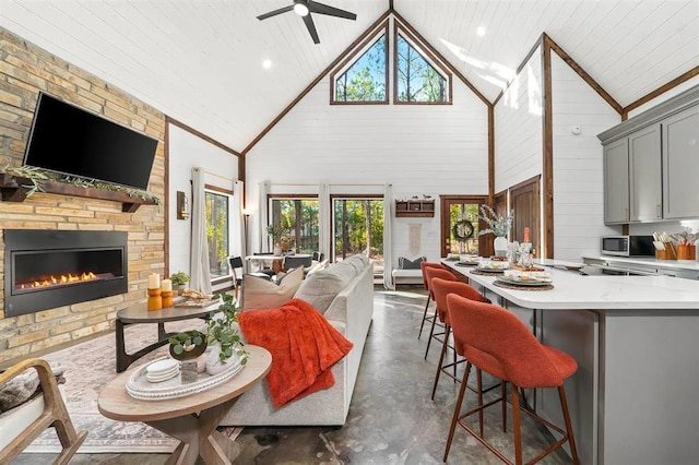 living room featuring ceiling fan, a fireplace, high vaulted ceiling, and a healthy amount of sunlight