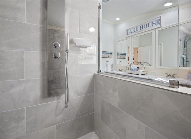 bathroom featuring vanity, ornamental molding, and tiled shower