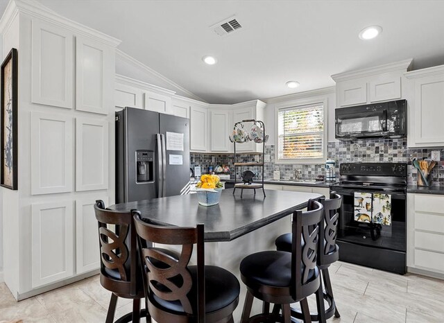 kitchen featuring backsplash, ornamental molding, vaulted ceiling, black appliances, and white cabinets