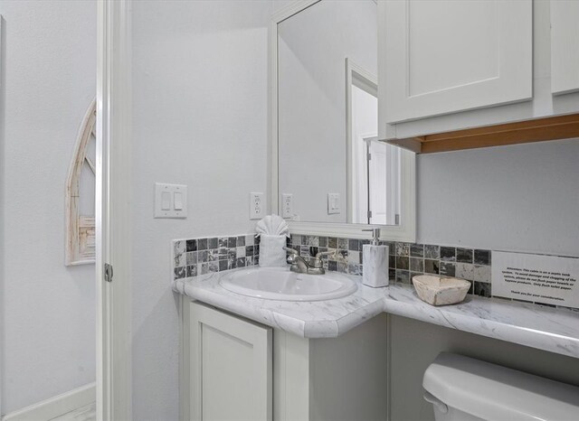 bathroom featuring vanity, toilet, and backsplash