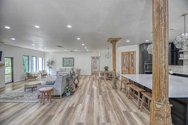 living room with decorative columns and light wood-type flooring