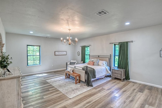 bedroom featuring a chandelier, light hardwood / wood-style floors, and multiple windows