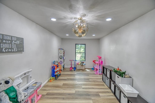 playroom with an inviting chandelier and light wood-type flooring