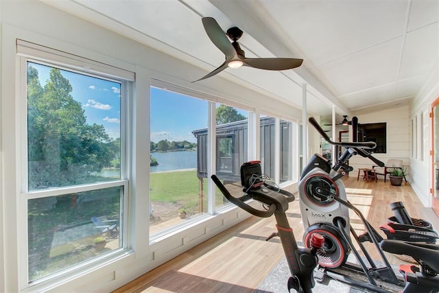 exercise room with a water view, a ceiling fan, and wood finished floors