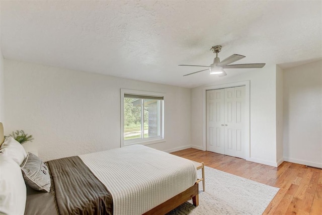 bedroom featuring baseboards, ceiling fan, a textured ceiling, light wood-type flooring, and a closet