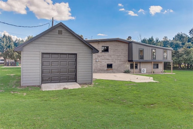 back of house featuring an outbuilding, brick siding, a yard, concrete driveway, and a garage