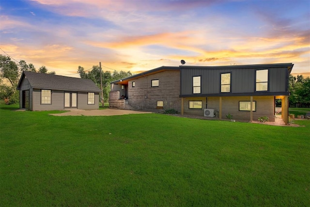 back of house at dusk featuring a yard, a patio area, ac unit, and an outdoor structure