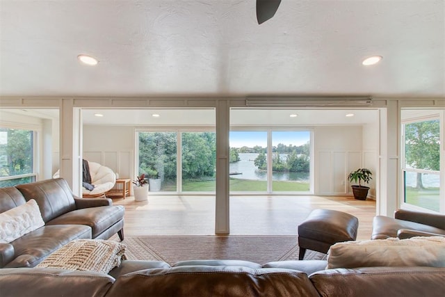 living area with a healthy amount of sunlight, a decorative wall, and wood finished floors