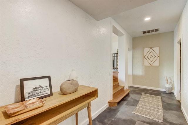 mudroom with concrete flooring, visible vents, a textured wall, and baseboards