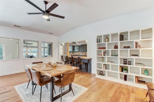 dining room with vaulted ceiling, light wood finished floors, and visible vents