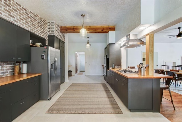 kitchen with a breakfast bar, stainless steel appliances, ventilation hood, open shelves, and wooden counters