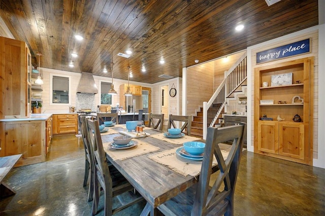 dining space with built in shelves, wooden ceiling, and wood walls