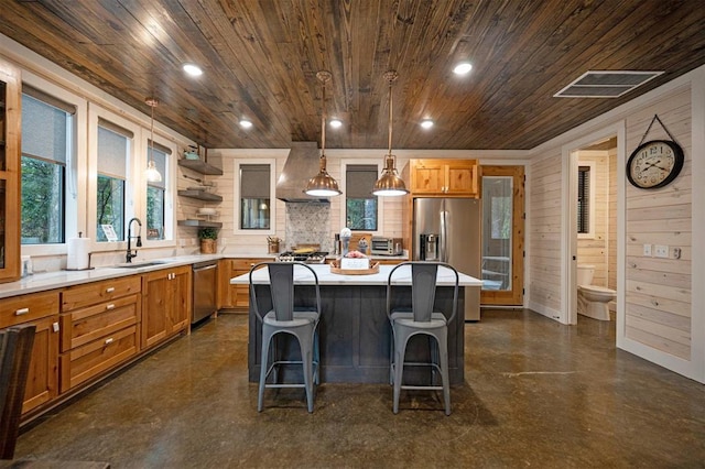 kitchen featuring wood walls, a center island, wooden ceiling, wall chimney exhaust hood, and stainless steel appliances