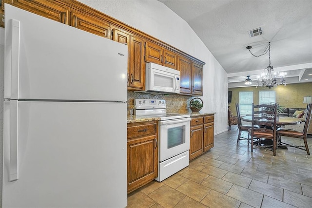 kitchen featuring tasteful backsplash, light stone counters, pendant lighting, a textured ceiling, and white appliances