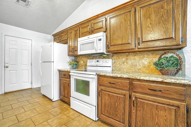 kitchen with light stone countertops, tasteful backsplash, a textured ceiling, lofted ceiling, and white appliances