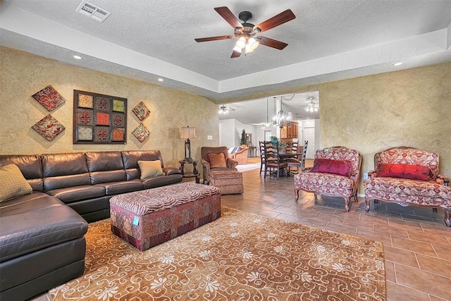 living room with tile patterned flooring, ceiling fan, and a textured ceiling