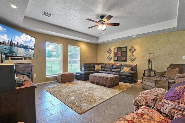 living room featuring a textured ceiling, a raised ceiling, and ceiling fan