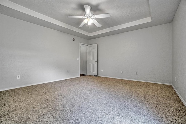 empty room with carpet flooring and a raised ceiling