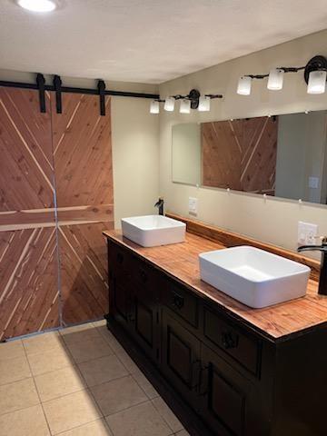 bathroom with tile patterned floors, vanity, and wood walls