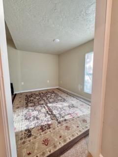 carpeted empty room featuring a textured ceiling