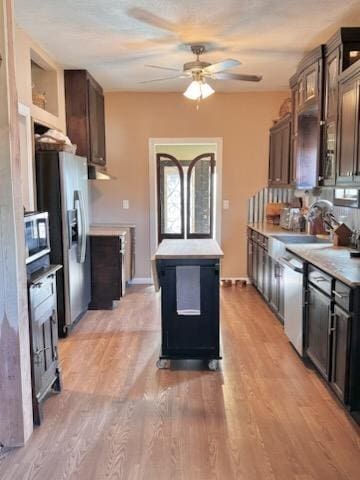 kitchen with dark brown cabinetry, ceiling fan, stainless steel appliances, light hardwood / wood-style floors, and a kitchen island