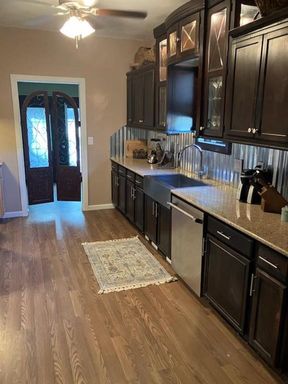 kitchen featuring decorative backsplash, light stone countertops, sink, wood-type flooring, and dishwasher