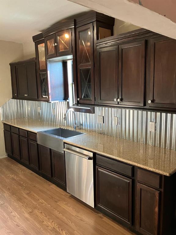 kitchen featuring dark brown cabinets, light wood-type flooring, stainless steel dishwasher, and sink