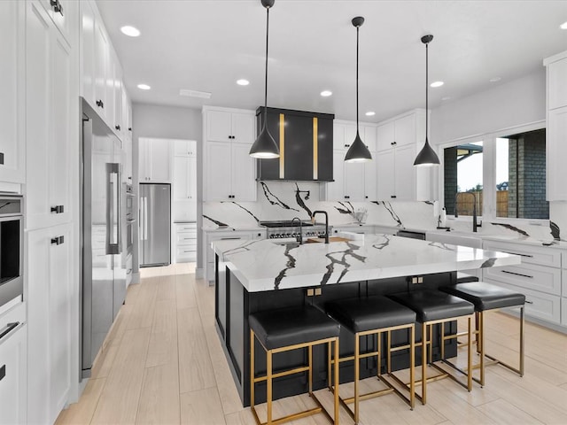 kitchen featuring white cabinetry, a large island with sink, light stone countertops, and a breakfast bar