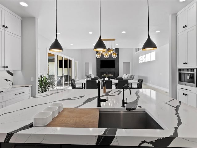 kitchen with light stone countertops, pendant lighting, and white cabinetry