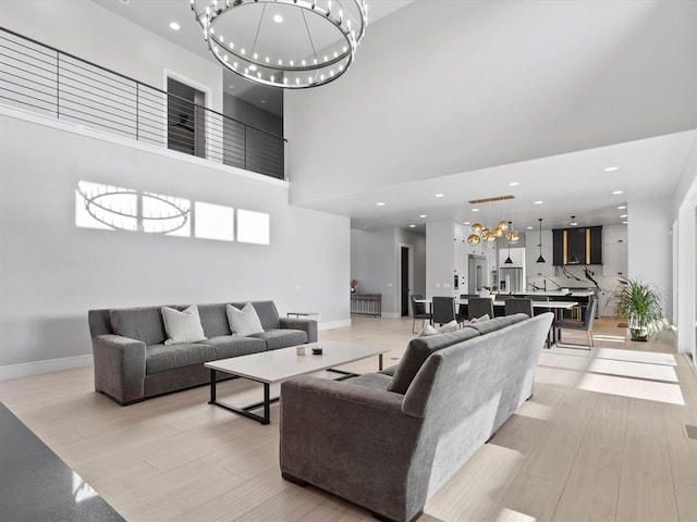 living room with light hardwood / wood-style floors, a high ceiling, and a chandelier