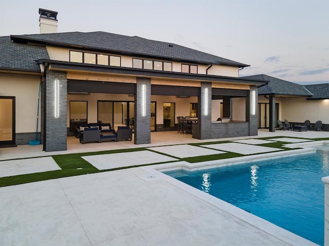 back house at dusk with an outdoor living space, a bar, and a patio