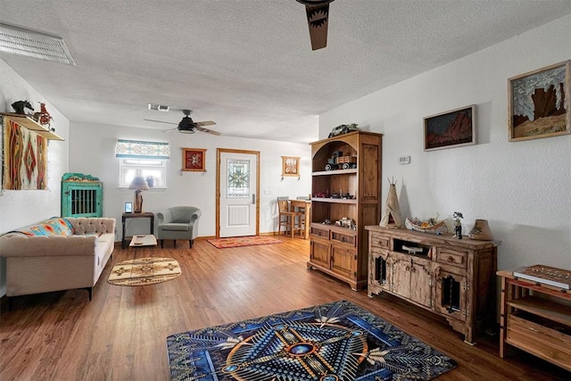 living room with ceiling fan, hardwood / wood-style floors, and a textured ceiling