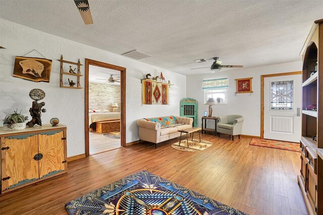 living room with ceiling fan, wood-type flooring, and a textured ceiling