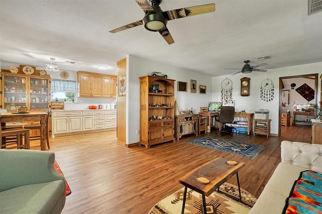 living room with ceiling fan, light hardwood / wood-style floors, and a textured ceiling