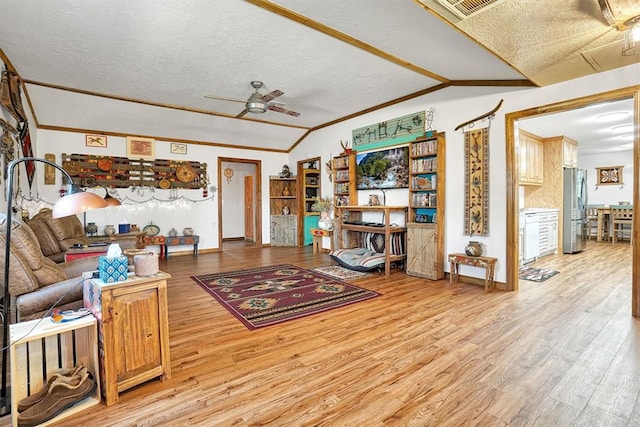 living room featuring ceiling fan, light hardwood / wood-style flooring, crown molding, lofted ceiling, and a textured ceiling