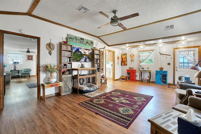 living room featuring hardwood / wood-style floors, vaulted ceiling with beams, ceiling fan, and a textured ceiling