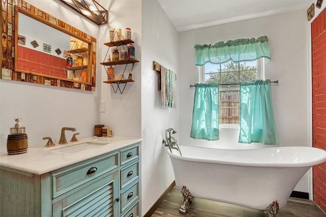 bathroom featuring vanity, hardwood / wood-style flooring, a bathing tub, and brick wall