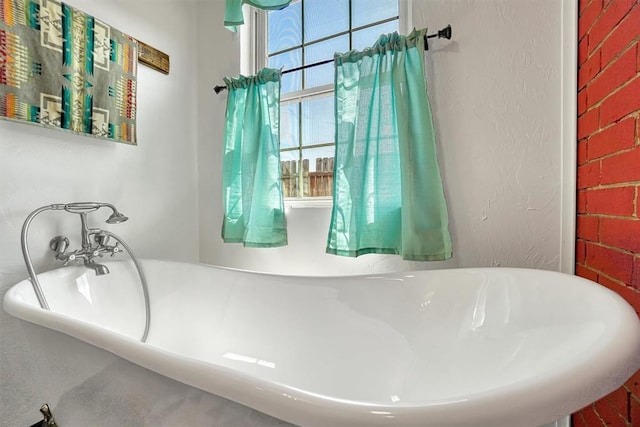 bathroom featuring a bathing tub and brick wall