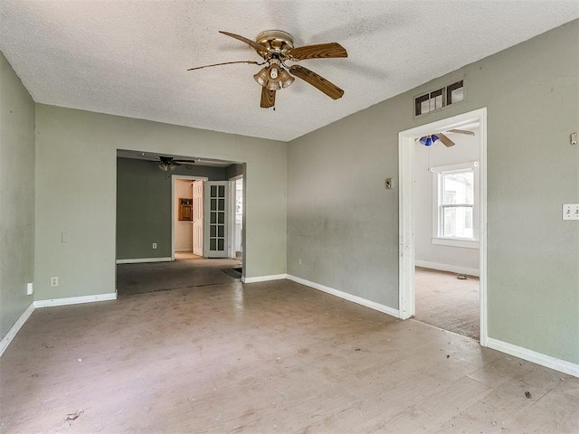 unfurnished room with ceiling fan and a textured ceiling