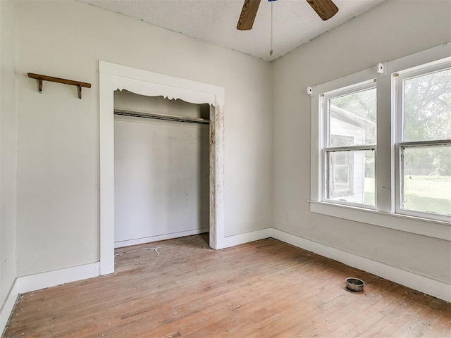 unfurnished bedroom with ceiling fan, a closet, a textured ceiling, and light hardwood / wood-style flooring