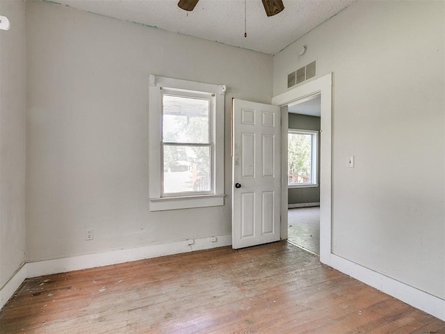 empty room with hardwood / wood-style floors, a wealth of natural light, and ceiling fan