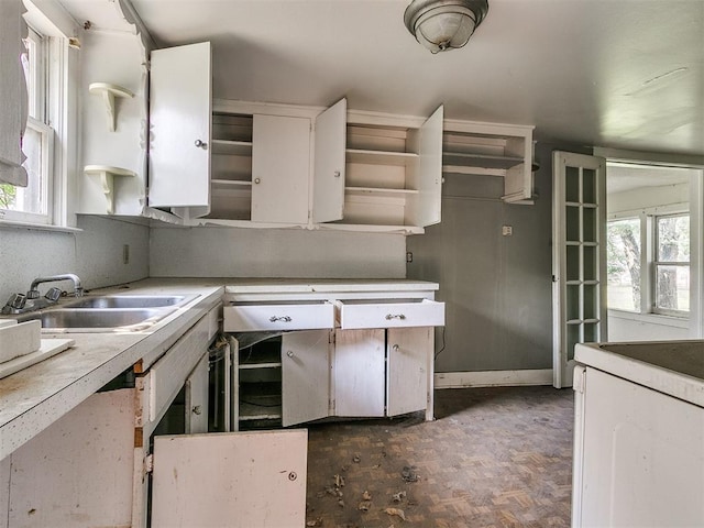 kitchen with dark parquet floors, a healthy amount of sunlight, white cabinetry, and sink