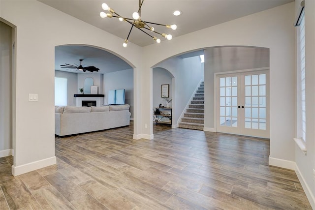 living room with french doors, ceiling fan with notable chandelier, and light hardwood / wood-style flooring