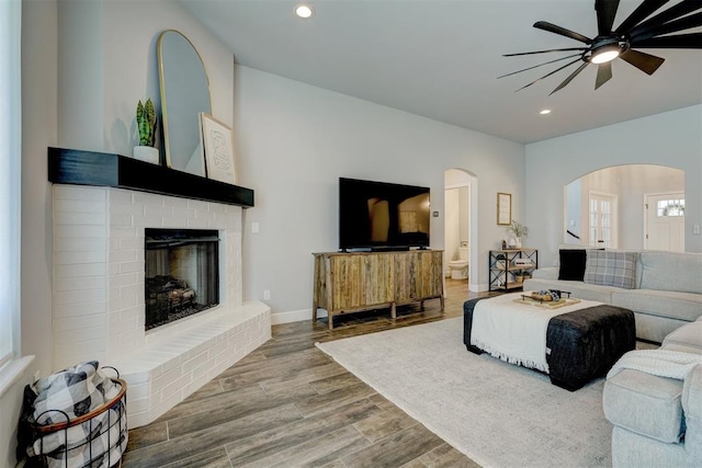 living room featuring hardwood / wood-style flooring, a brick fireplace, and ceiling fan