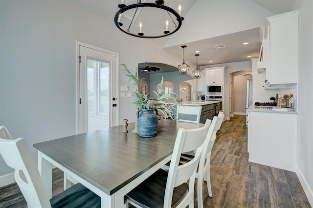 dining room with sink, dark hardwood / wood-style flooring, lofted ceiling, and an inviting chandelier